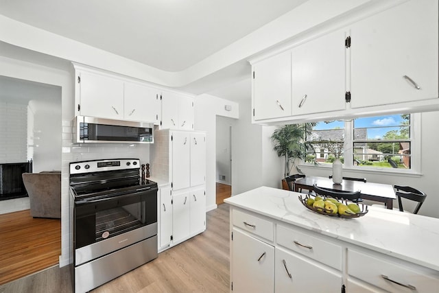 1464 Kent St, Saint Paul, MN 55117 - kitchen featuring appliances with stainless steel finishes, light wood-style floors, backsplash, white cabinetry, and light stone counters