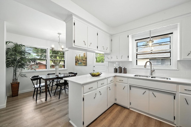 1464 Kent St, Saint Paul, MN 55117 - kitchen with a peninsula, tasteful backsplash, white cabinets, light countertops, and wood finished floors