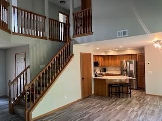 1129 Willow Trl, Farmington, MN 55024 - kitchen featuring stainless steel fridge, a towering ceiling, wood finished floors, brown cabinets, and a peninsula