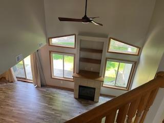 1129 Willow Trl, Farmington, MN 55024 - unfurnished living room with a high ceiling, ceiling fan, wood finished floors, and a fireplace