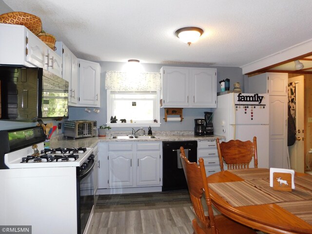 37452 Deer St, Aitkin, MN 56431 - kitchen with black appliances, light countertops, white cabinets, and wood finished floors