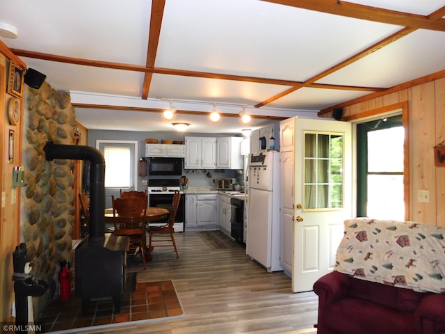 37452 Deer St, Aitkin, MN 56431 - kitchen featuring black appliances, a wood stove, light wood-style floors, wooden walls, and light countertops