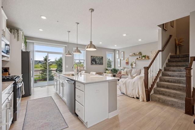 18874 72nd Pl N, Maple Grove, MN 55311 - kitchen featuring appliances with stainless steel finishes, light wood-type flooring, a center island with sink, white cabinetry, and light countertops