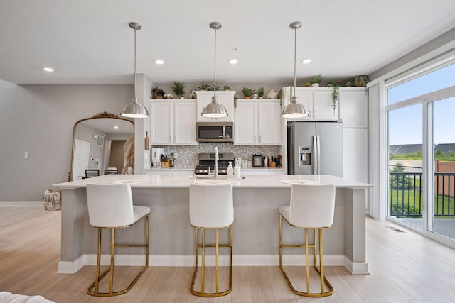 18874 72nd Pl N, Maple Grove, MN 55311 - kitchen with stainless steel appliances, tasteful backsplash, light wood finished floors, an island with sink, and recessed lighting
