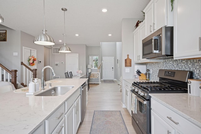 18874 72nd Pl N, Maple Grove, MN 55311 - kitchen featuring stainless steel appliances, white cabinets, backsplash, light wood-type flooring, and light stone countertops