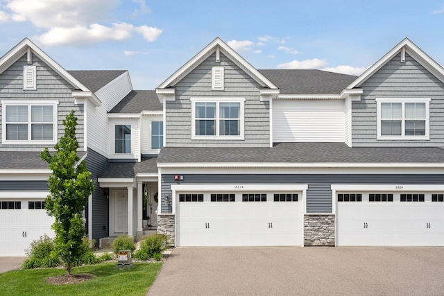 18874 72nd Pl N, Maple Grove, MN 55311 - townhome / multi-family property featuring asphalt driveway, an attached garage, stone siding, and a shingled roof