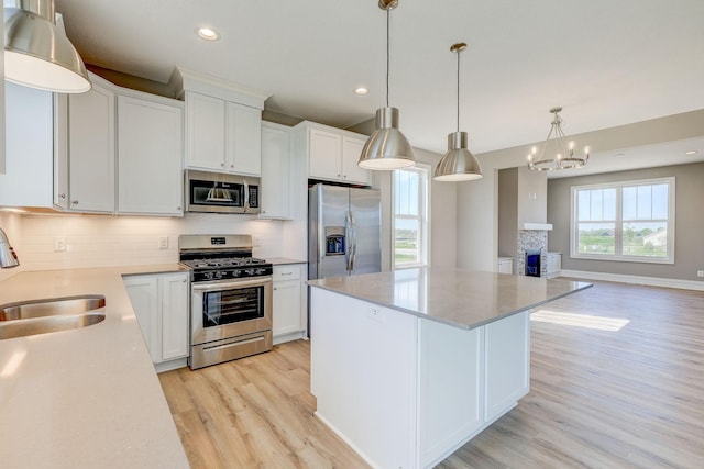 2885 Trinity Dr, Shakopee, MN 55379 - kitchen with appliances with stainless steel finishes, light wood-style flooring, backsplash, a kitchen island, and white cabinetry