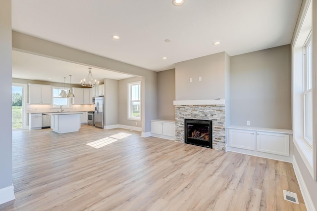 2885 Trinity Dr, Shakopee, MN 55379 - unfurnished living room featuring light wood-style floors, a chandelier, recessed lighting, and a stone fireplace