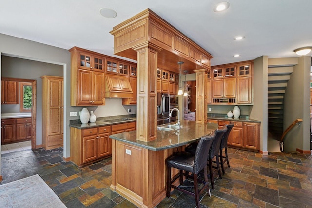 15208 Fairway Heights Rd NW, Prior Lake, MN 55372 - kitchen featuring stone tile flooring, black electric cooktop, premium range hood, brown cabinets, and recessed lighting