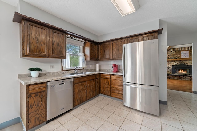 5510 Thompson Hill Rd, Proctor, MN 55810 - kitchen featuring stainless steel appliances, light countertops, a brick fireplace, a textured ceiling, and light tile patterned flooring