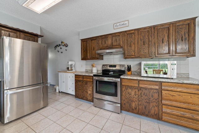 5510 Thompson Hill Rd, Proctor, MN 55810 - kitchen with stainless steel appliances, under cabinet range hood, light tile patterned flooring, decorative backsplash, and a textured ceiling