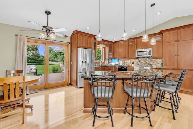 4619 Heather Way N, Oakdale, MN 55128 - kitchen featuring stainless steel appliances, ceiling fan, dark stone countertops, backsplash, and a center island