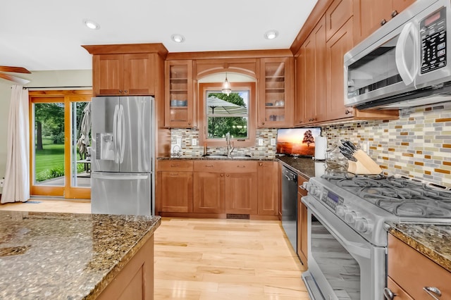 4619 Heather Way N, Oakdale, MN 55128 - kitchen with appliances with stainless steel finishes, dark stone countertops, brown cabinets, healthy amount of natural light, and recessed lighting