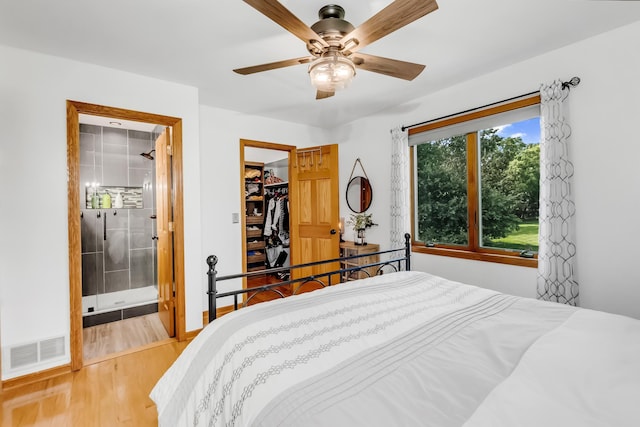 4619 Heather Way N, Oakdale, MN 55128 - bedroom featuring wood finished floors, ensuite bath, a spacious closet, a ceiling fan, and a closet