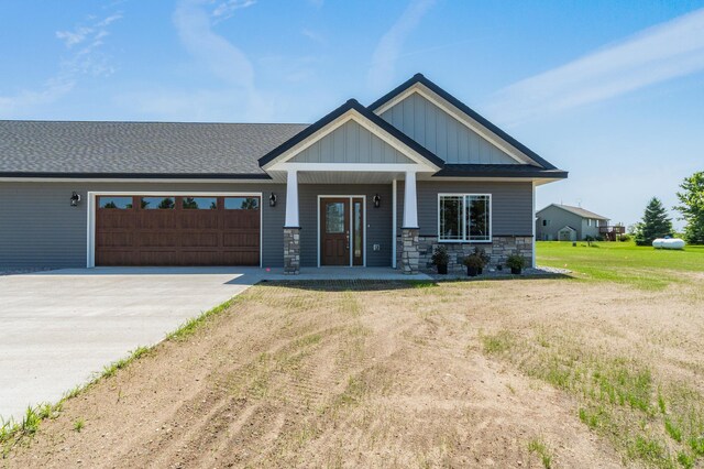 607 Colfax St, Parkers Prairie, MN 56361 - view of front of home with an attached garage, driveway, stone siding, board and batten siding, and a porch