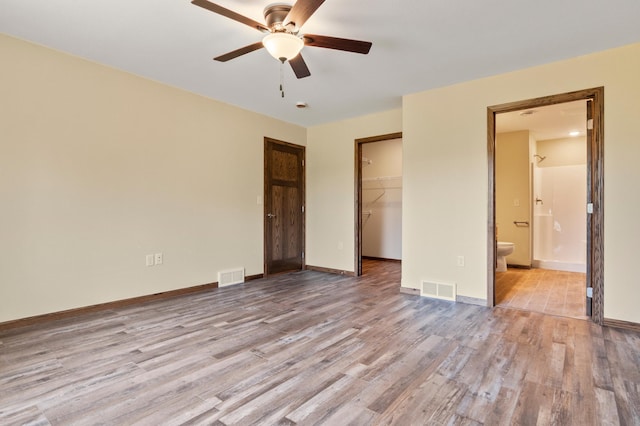 607 Colfax St, Parkers Prairie, MN 56361 - unfurnished bedroom with wood finished floors, a closet, a walk in closet, and connected bathroom