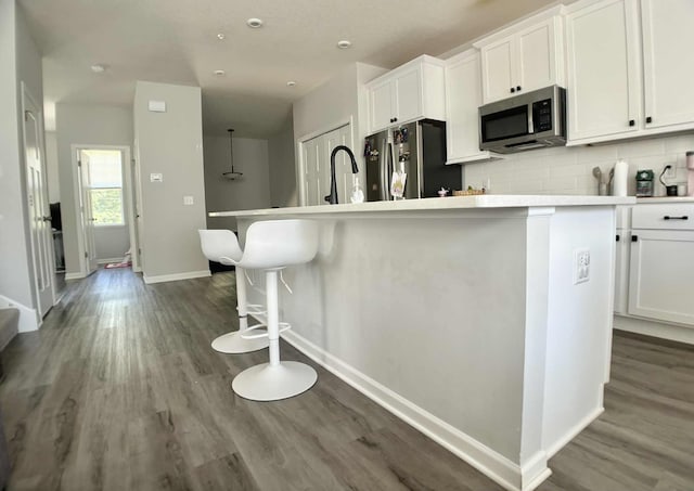 7628 Carla Path, Inver Grove Heights, MN 55076 - kitchen featuring stainless steel appliances, white cabinetry, tasteful backsplash, wood finished floors, and an island with sink