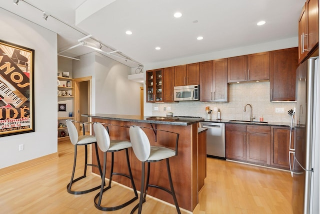 150 2nd St NE Unit B302, Minneapolis, MN 55413 - kitchen with appliances with stainless steel finishes, dark countertops, a center island, a kitchen breakfast bar, and light wood-style floors