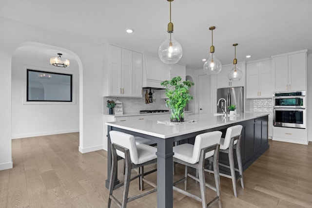 9612 Iron Horse Rd, Woodbury, MN 55129 - kitchen with recessed lighting, stainless steel appliances, backsplash, light countertops, and light wood finished floors