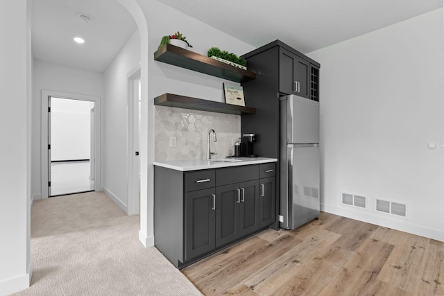 9612 Iron Horse Rd, Woodbury, MN 55129 - kitchen with freestanding refrigerator, open shelves, light countertops, backsplash, and light wood-style floors
