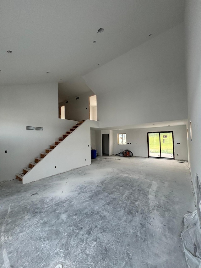 3641 18th St SE, Rochester, MN 55904 - unfurnished living room featuring a towering ceiling, stairs, and concrete floors