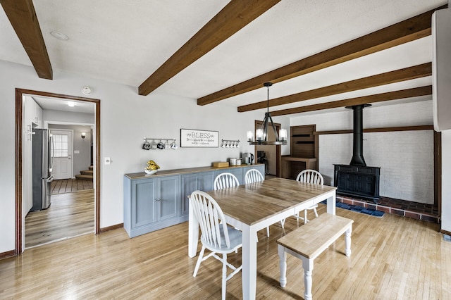 11542 Xavis St NW, Coon Rapids, MN 55433 - dining area featuring light wood-style flooring, a wood stove, beamed ceiling, stairway, and a chandelier