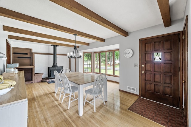 11542 Xavis St NW, Coon Rapids, MN 55433 - dining room featuring light wood-type flooring, beam ceiling, a wood stove, and a chandelier