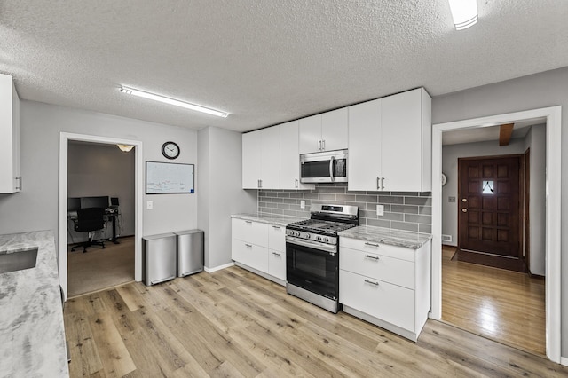 11542 Xavis St NW, Coon Rapids, MN 55433 - kitchen with appliances with stainless steel finishes, light wood-type flooring, backsplash, a textured ceiling, and white cabinetry