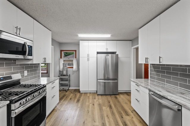 11542 Xavis St NW, Coon Rapids, MN 55433 - kitchen featuring stainless steel appliances, a textured ceiling, decorative backsplash, light wood-type flooring, and white cabinets