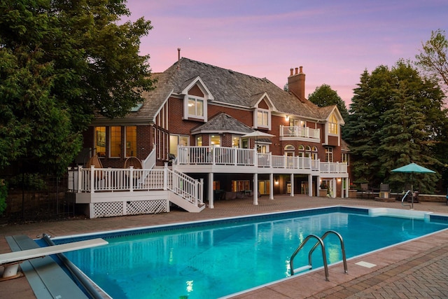 10 Apple Orchard Ct, Dellwood, MN 55110 - back of house at dusk with a wooden deck, an outdoor pool, a chimney, stairway, and a patio