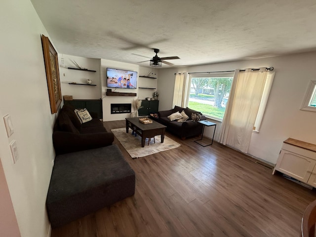 122 3rd St E, Morgan, MN 56266 - living room featuring dark wood-style floors, a ceiling fan, and a glass covered fireplace