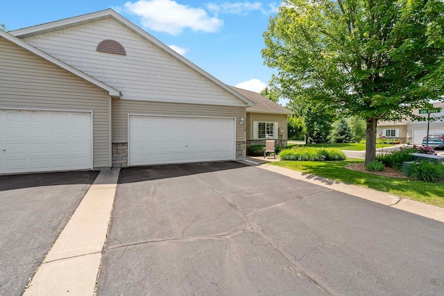 1112 Iris Dr, White Bear Twp, MN 55127 - view of front of house featuring stone siding, driveway, and an attached garage