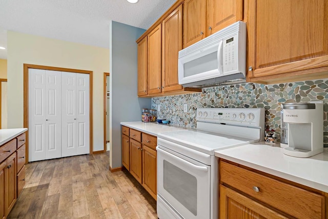 1112 Iris Dr, White Bear Twp, MN 55127 - kitchen featuring white appliances, tasteful backsplash, brown cabinetry, light wood-style floors, and light countertops