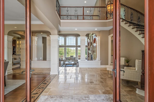 18901 Brookwood Rd, Prior Lake, MN 55372 - entrance foyer featuring decorative columns, a high ceiling, stone tile flooring, crown molding, and arched walkways