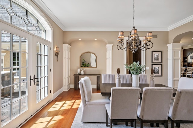 18901 Brookwood Rd, Prior Lake, MN 55372 - dining space with arched walkways, a chandelier, crown molding, light wood-style flooring, and ornate columns