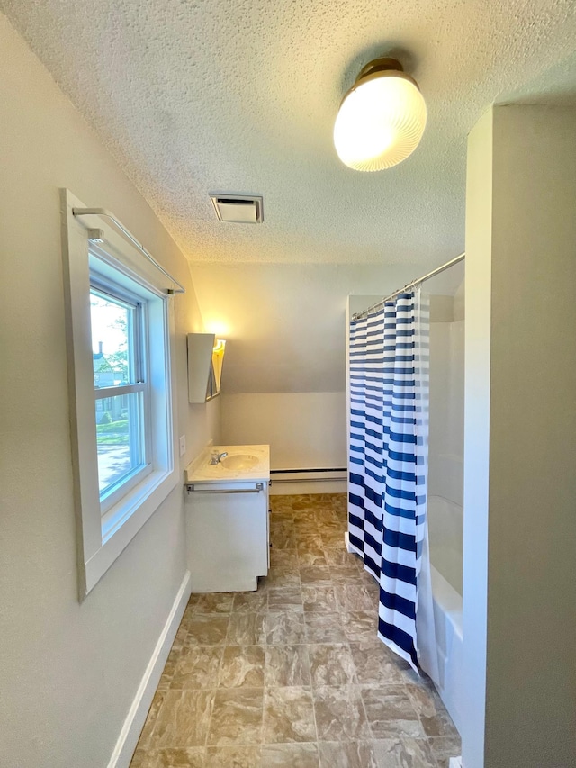 422 Sanborn St, Springfield, MN 56087 - bathroom featuring a textured ceiling, vanity, a baseboard radiator, stone finish flooring, and shower / bath combo