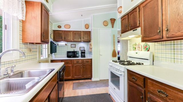 2104 US Highway 8, Stanley Twp, WI 54822 - kitchen with gas range gas stove, under cabinet range hood, backsplash, light wood-style floors, and light countertops