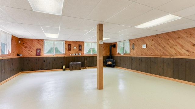 2104 US Highway 8, Stanley Twp, WI 54822 - basement featuring wood walls, a wood stove, and a paneled ceiling