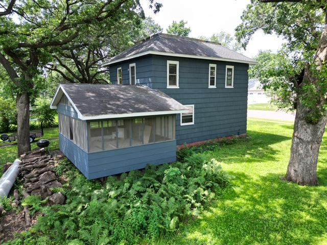 311 Grove St, Redwood Falls, MN 56283 - back of property featuring a shingled roof, a sunroom, and a yard