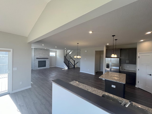 3790 Thrush St, Shakopee, MN 55379 - kitchen featuring stainless steel refrigerator with ice dispenser, dark wood-style flooring, a stone fireplace, a kitchen island, and vaulted ceiling