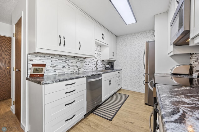 2575 Pacific Dr S Unit 301, Fargo, ND 58103 - kitchen with stainless steel appliances, light wood-style floors, white cabinetry, tasteful backsplash, and wallpapered walls