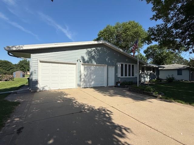 2411 Douglas St, Windom, MN 56101 - view of side of property featuring a garage, driveway, and a yard