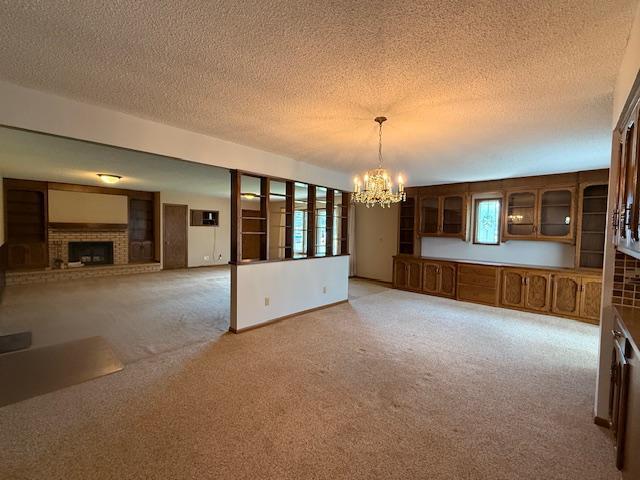 2411 Douglas St, Windom, MN 56101 - unfurnished dining area featuring light colored carpet, a chandelier, a brick fireplace, and a textured ceiling