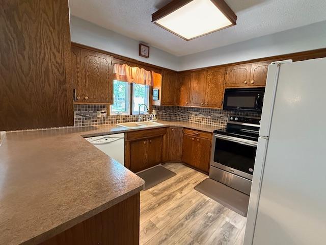 2411 Douglas St, Windom, MN 56101 - kitchen featuring white appliances, tasteful backsplash, light wood finished floors, and brown cabinets