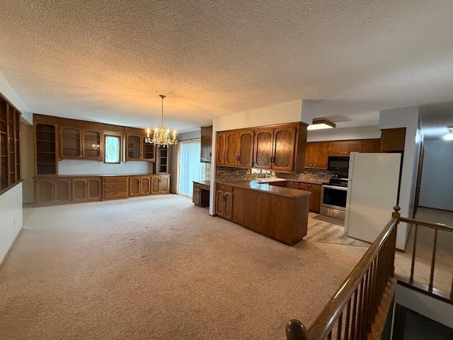 2411 Douglas St, Windom, MN 56101 - kitchen featuring freestanding refrigerator, black microwave, range, a chandelier, and a peninsula