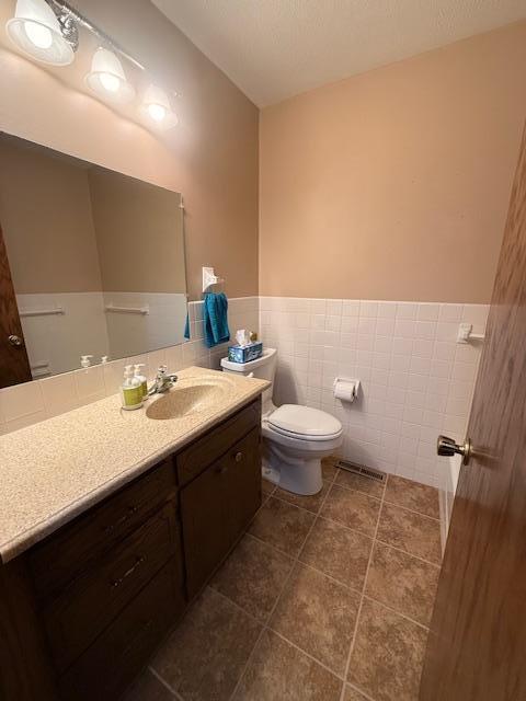 2411 Douglas St, Windom, MN 56101 - half bathroom with vanity, tile walls, a wainscoted wall, and tile patterned floors