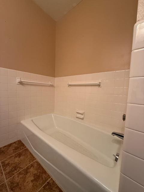 2411 Douglas St, Windom, MN 56101 - full bath featuring tile patterned flooring, a bath, tile walls, and a wainscoted wall