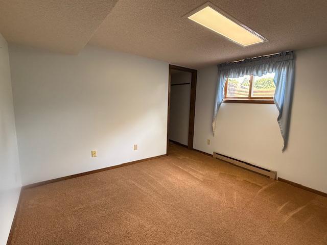 2411 Douglas St, Windom, MN 56101 - empty room featuring a baseboard radiator, carpet flooring, and a textured ceiling