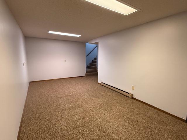 2411 Douglas St, Windom, MN 56101 - spare room with baseboard heating, carpet floors, and stairs