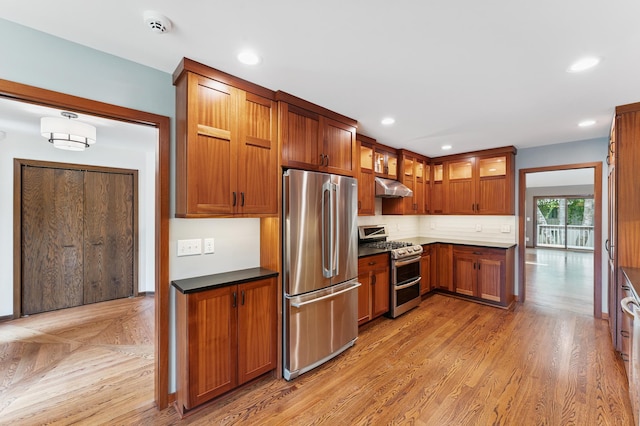 1775 Lexington Ave S Unit 26, Lilydale, MN 55118 - kitchen with stainless steel appliances, under cabinet range hood, glass insert cabinets, brown cabinetry, and dark countertops